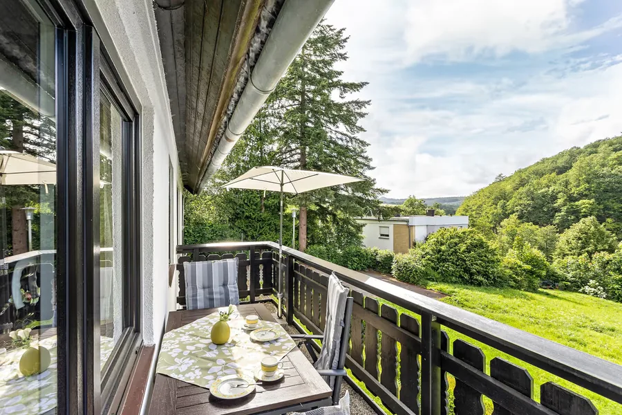 Gedeckter Tisch auf dem Balkon mit freiem Blick über Wiesen und Wald